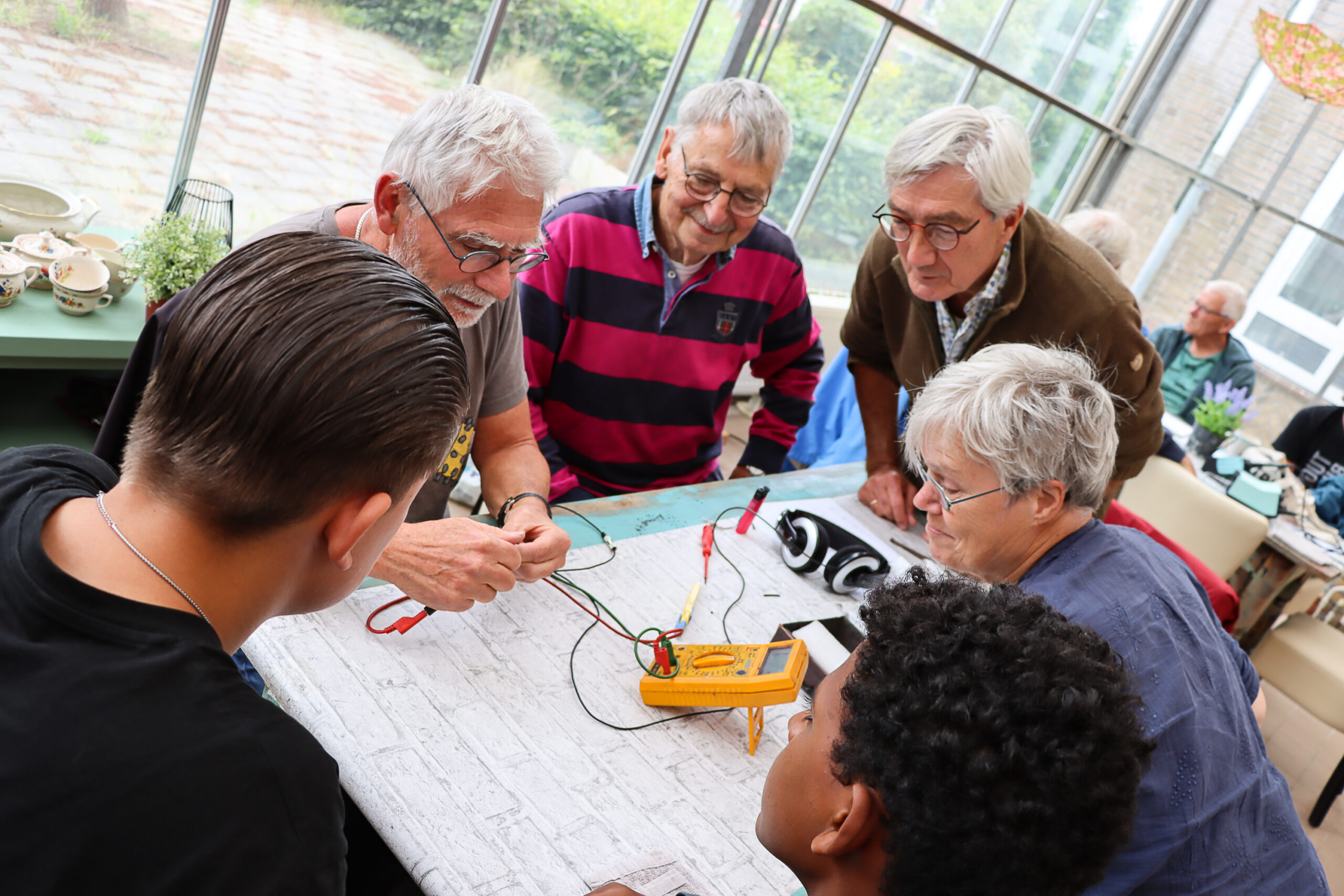 Twee studenten en vier reparateurs meten spanning tijdens een reparatie.