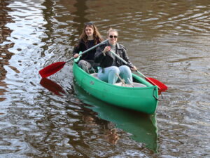 Twee jonge vrouwen, stagiaires, zitten in een kano op de gracht van Zwolle. Ze lachen.